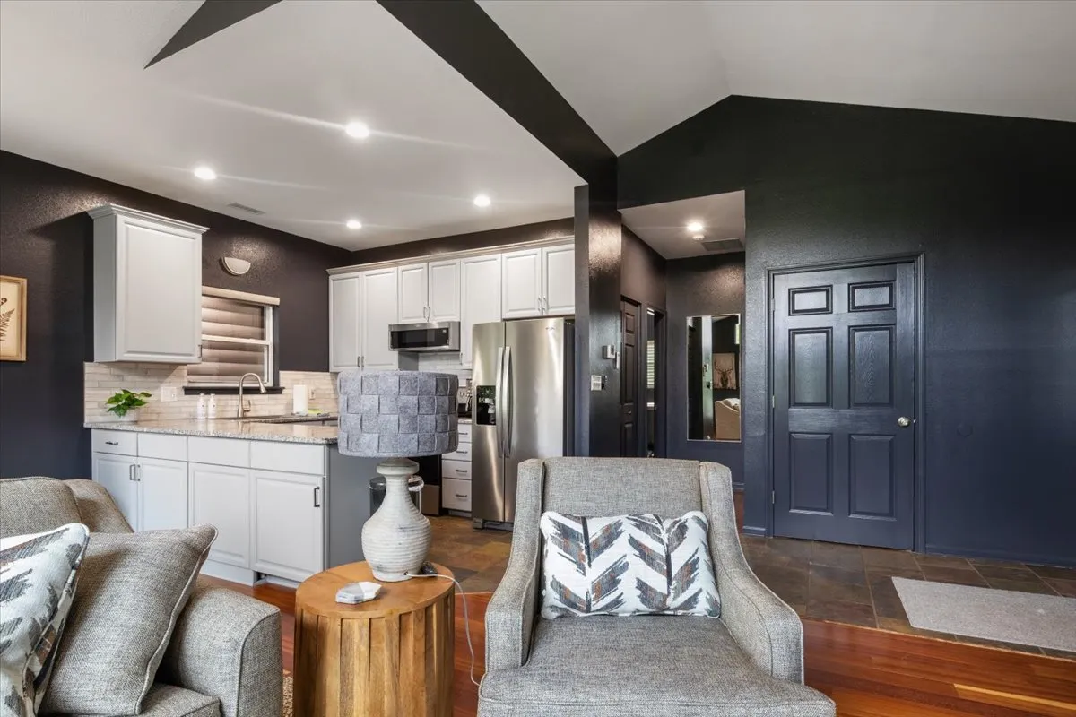 This image showcases the kitchen area with a comfortable seating arrangement and a decorative lamp. It highlights the open-concept layout and modern touches, giving a sense of the space where cooking, entertaining, and relaxing can occur seamlessly. The warm, contemporary decor reflects a cozy atmosphere perfect for communal gatherings.