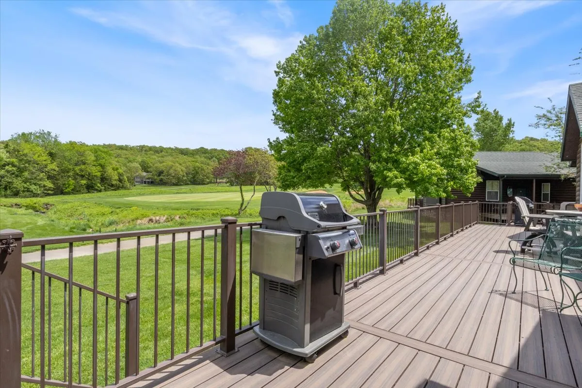 This exterior image features a private deck set against a backdrop of lush greenery and distant trees. The deck is equipped with a grill and outdoor seating, perfectly situated for barbecuing, dining, or simply relaxing amidst nature. The scene captures the relaxed, welcoming atmosphere of a resort-style outdoor living space, with a strong sense of privacy and comfort.