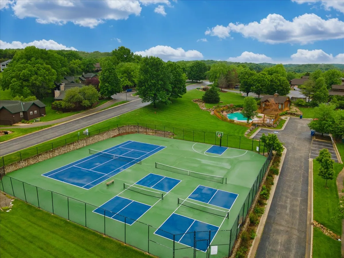 An energetic scene highlighting the community’s vibrant recreational core: tennis courts, a basketball court, and a sparkling swimming pool, all surrounded by lush greenery. The outdoor spaces are bustling with opportunity for fun and relaxation.